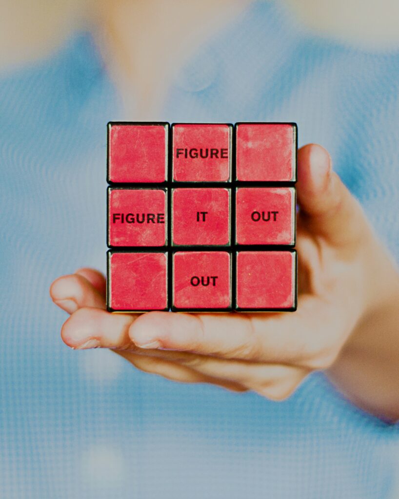 A hand holding a Rubiks cube with the words Figure It Out written on the side.