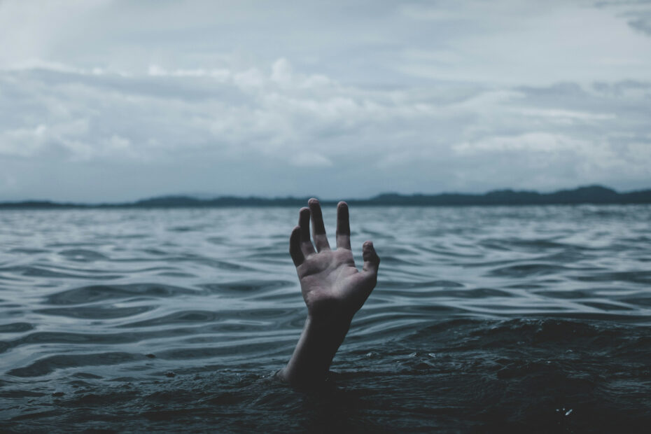 A hand reaches out from the sea, symbolising drowning. Being chronically overstimulated can make you feel like you’re drowning … in noise.